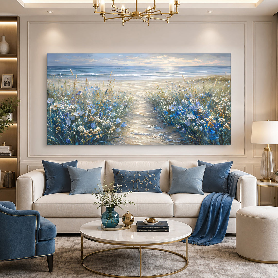 Quadro Caminho para o Mar acima do sofá com almofadas azuis, sob lustre dourado