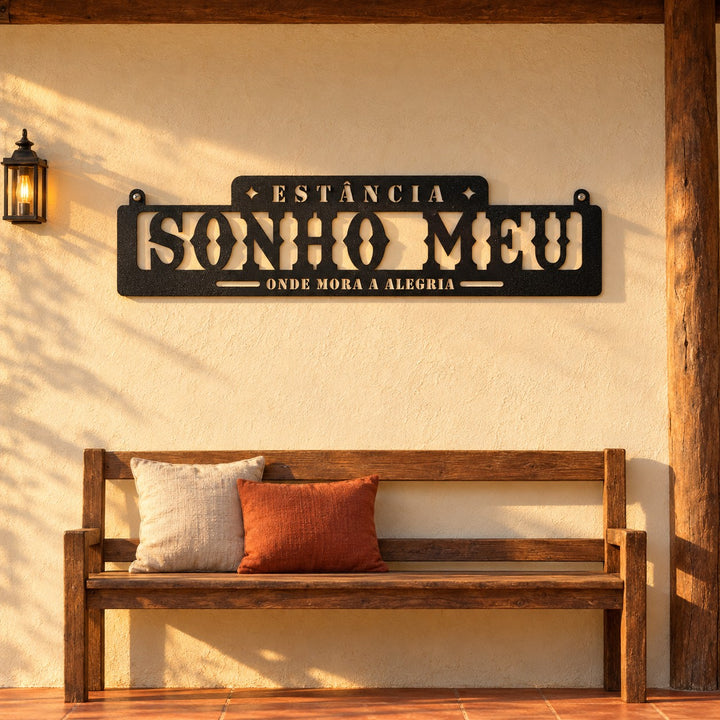 Placa Estância Sonho Meu em metal preto, tamanho 180 x 45 cm, na parede da varanda acima do banco