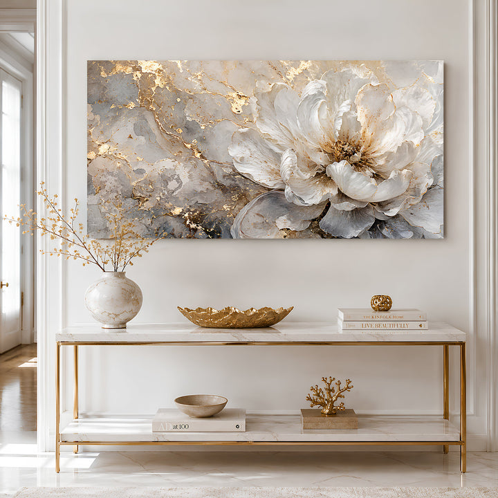 Quadro Flor de Mármore acima de aparador branco e dourado com vaso e galhos floridos
